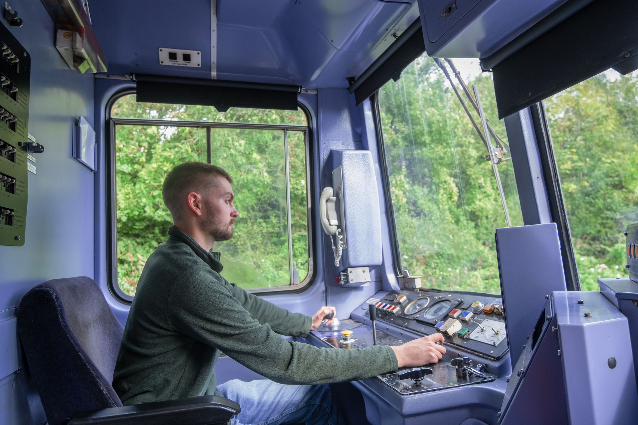 A young train driver operating the controls of a commuter train, Devon UK.