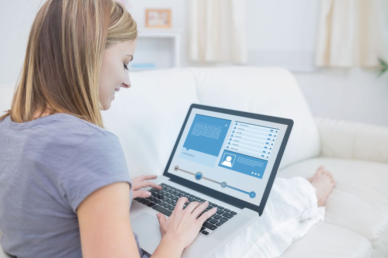Woman sitting on couch and checking social media profile with her laptop