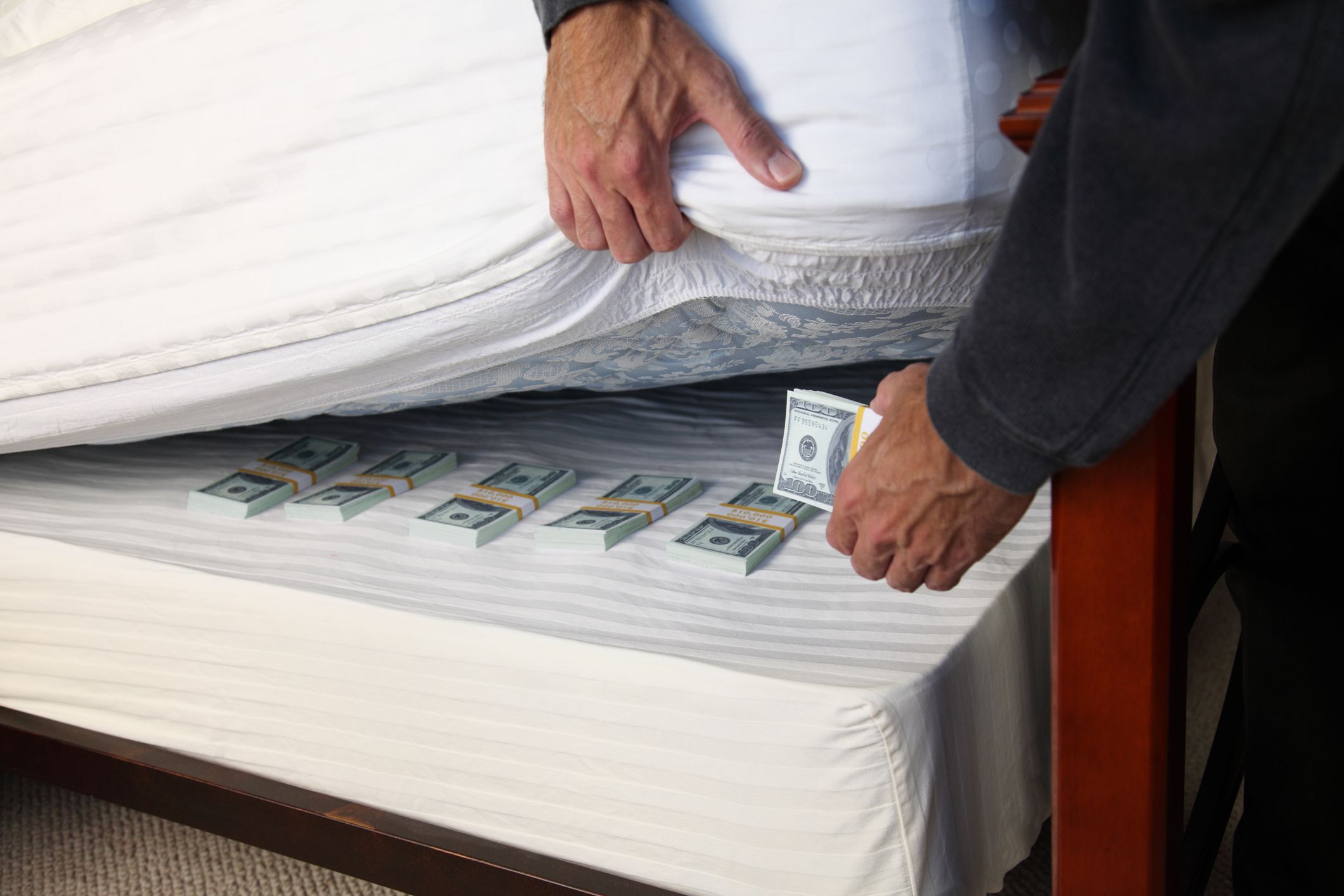 Man hides a stack of bills under his mattress.