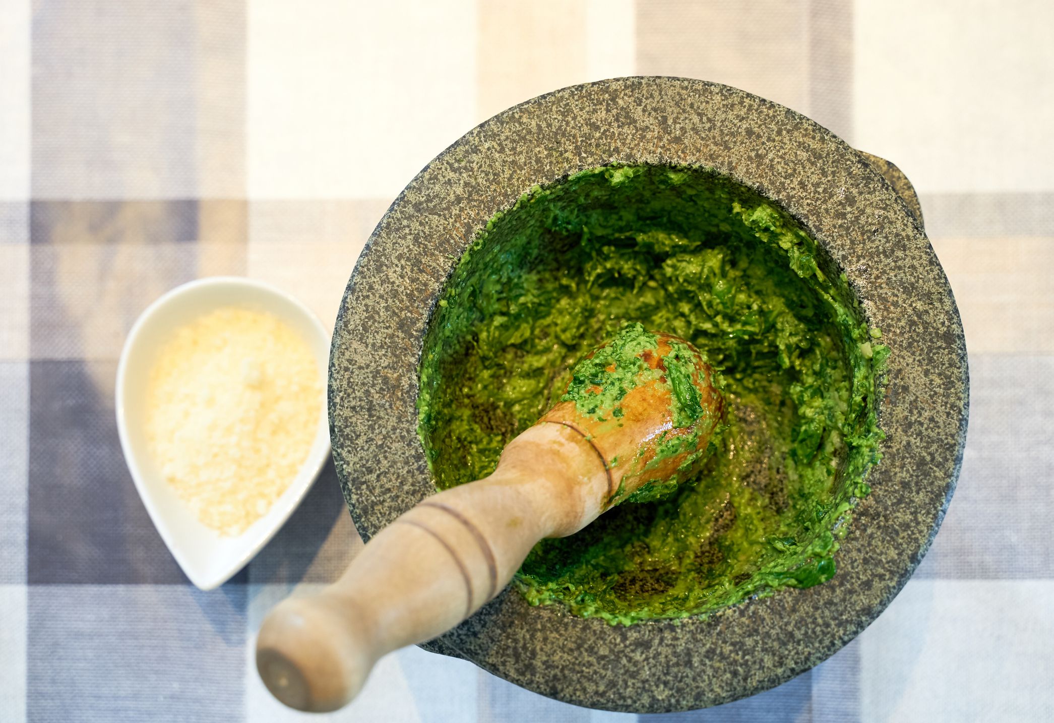 with basil, olive oil, pine nuts, parmesan cheese and garlic crush in a mortar with a wooden pestle