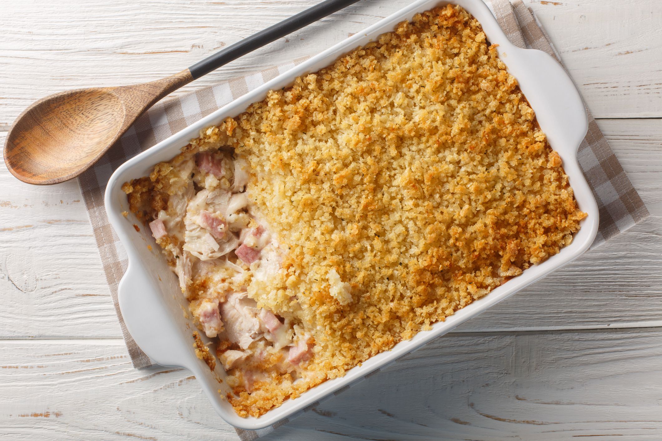Chicken Cordon Bleu Casserole with chicken breast, chopped ham and Swiss cheese layered with creamy sauce and Panko breadcrumbs close up in the baking dish. Horizontal top view from above