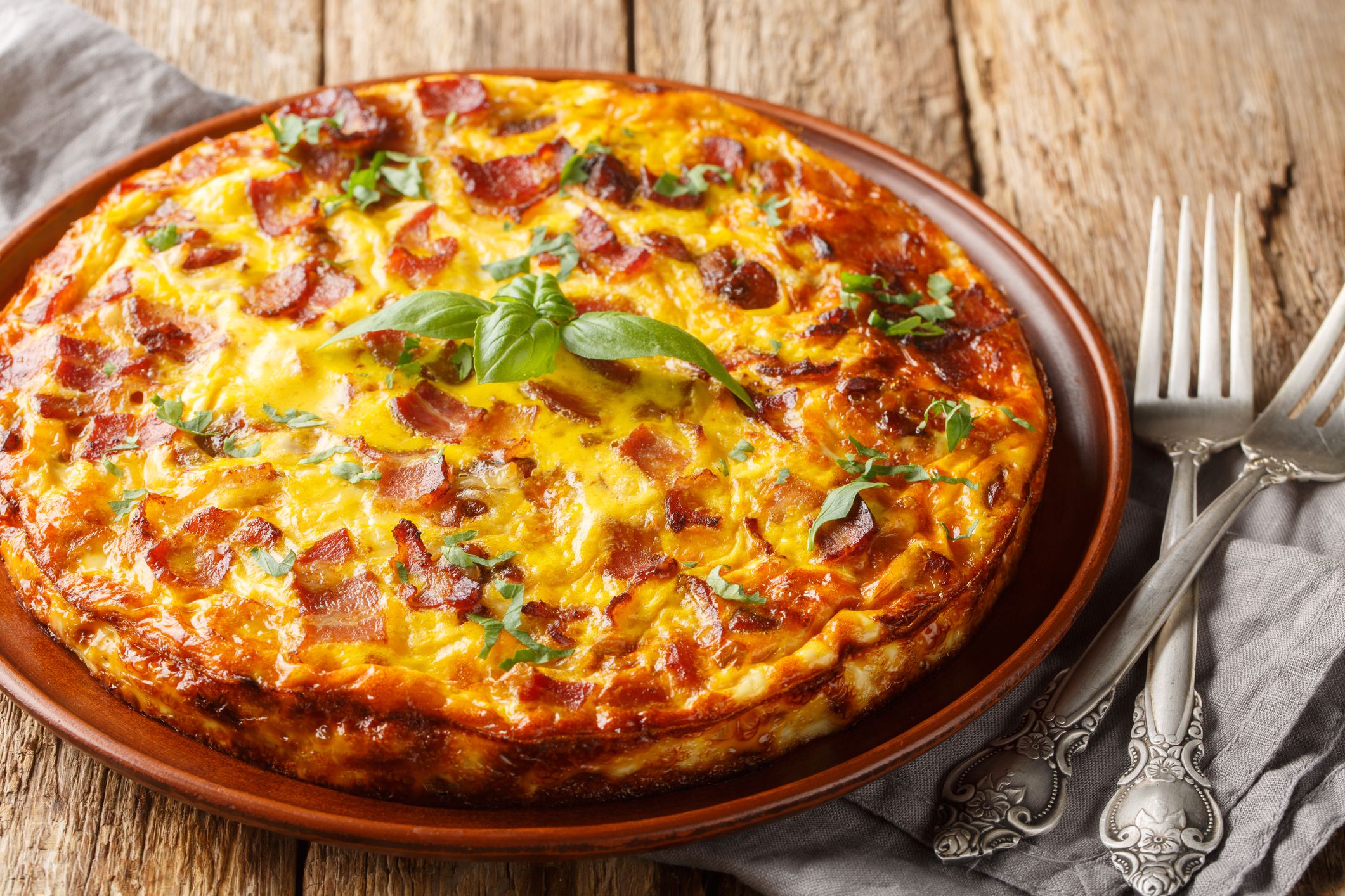 Frittata with chicken, cheese, eggs, bacon and herbs close-up in a plate on the table. Horizontal