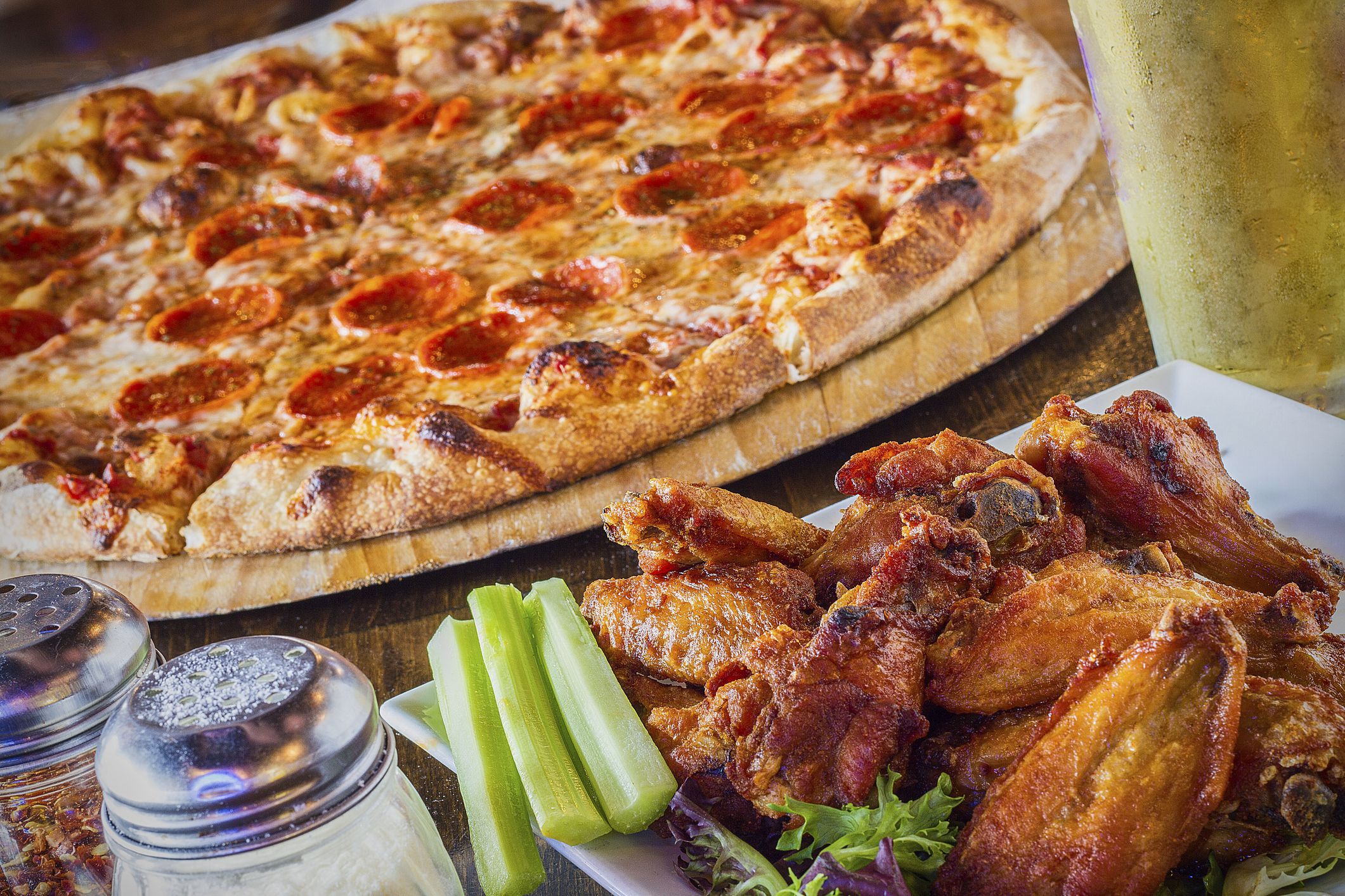 pepperoni pizza with buffalo chicken wings and a pint of beer