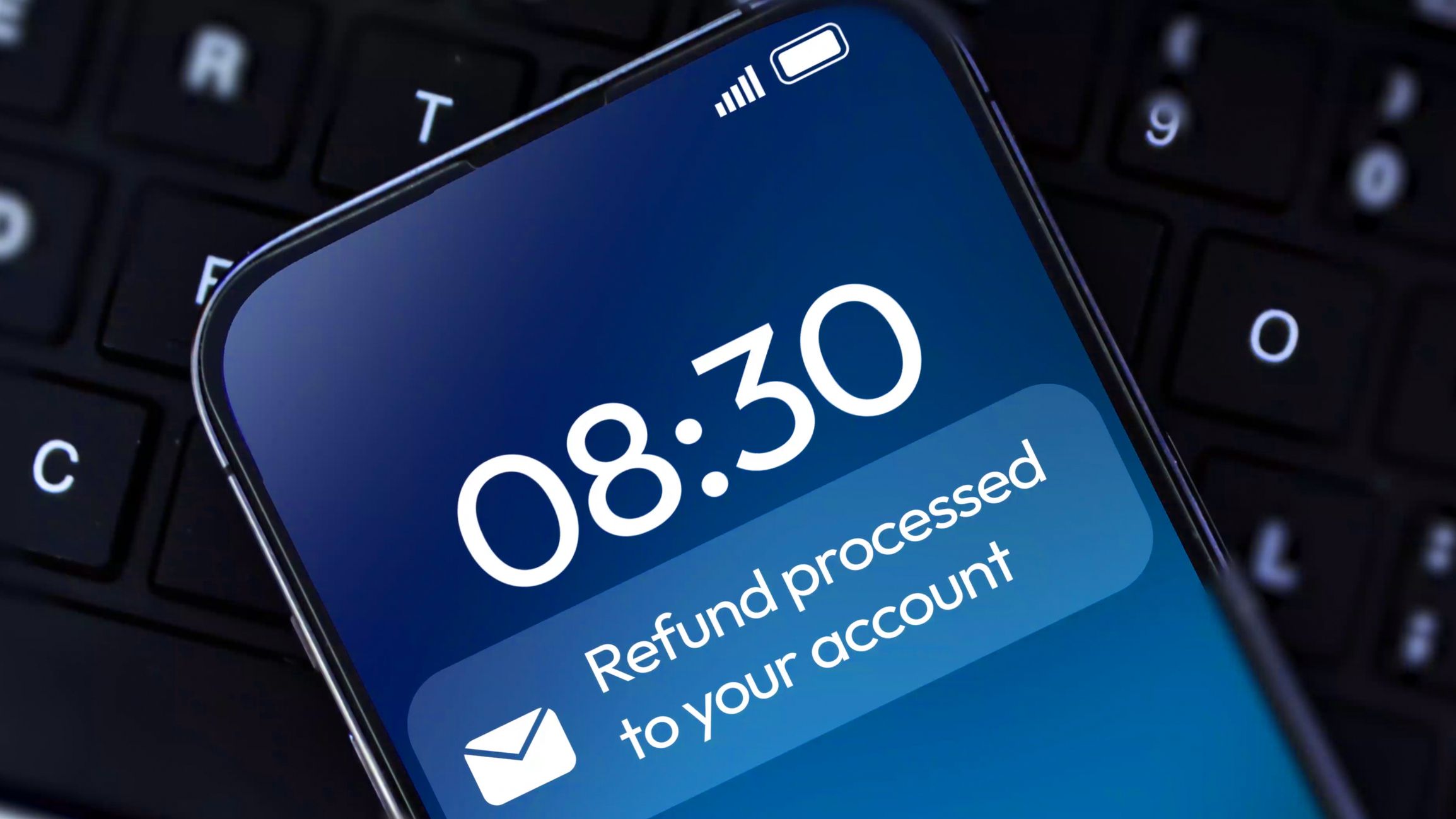 Refund processing into the account notification on smartphone screen with laptop in the backdrop. Online banking, money, finance concept