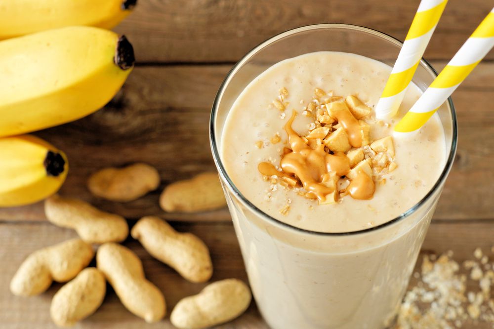 Peanut-butter banana oat smoothie on rustic wood with scattered ingredients