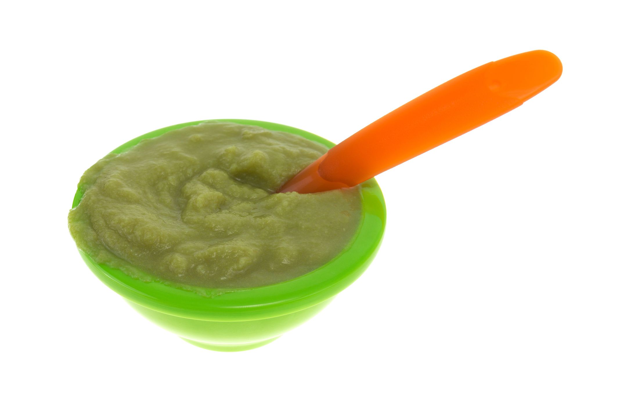 A serving of green peas baby food in a small bowl with an orange spoon inserted into the mush isolated on a white background.