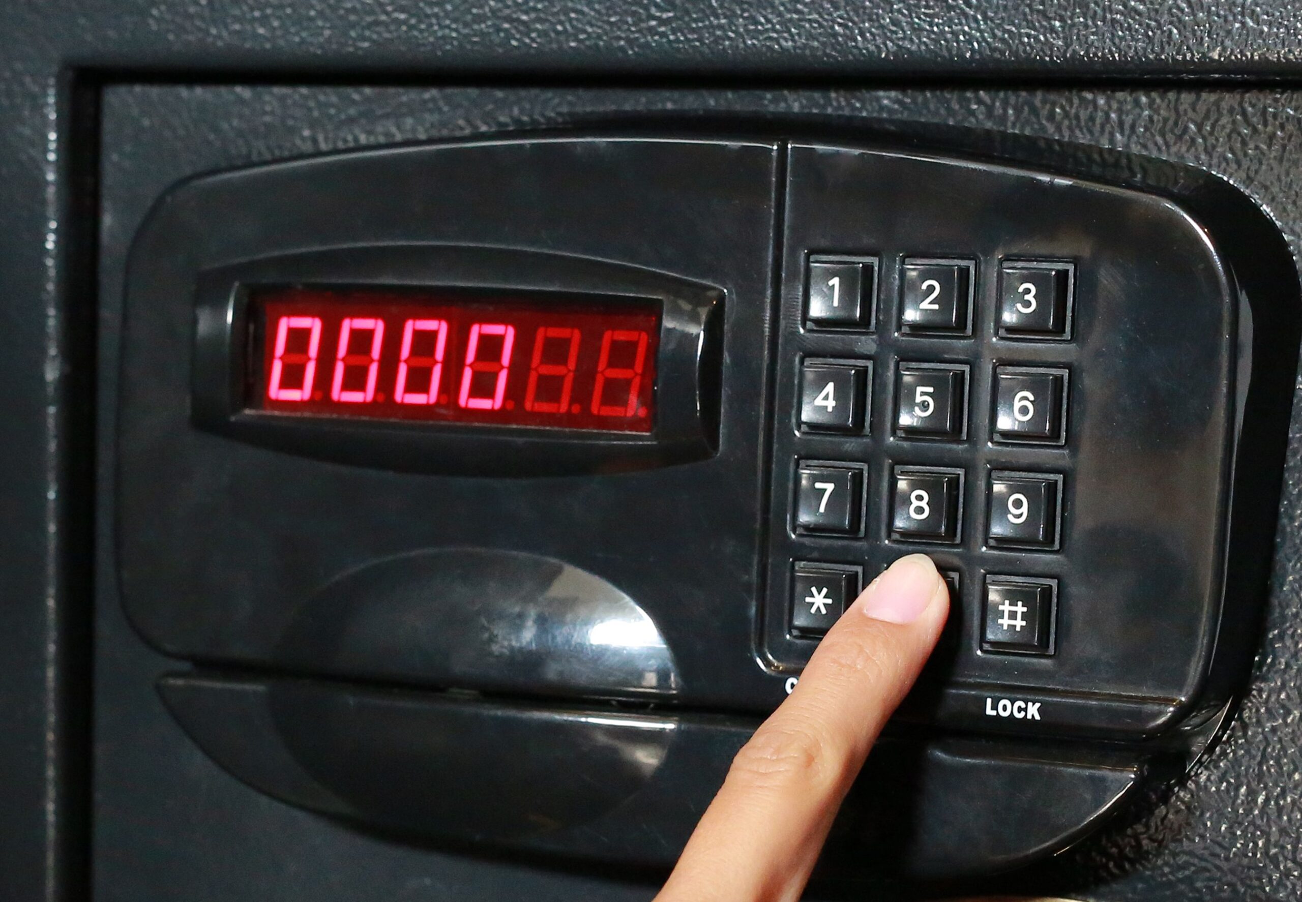 Hand press key on black safety box.