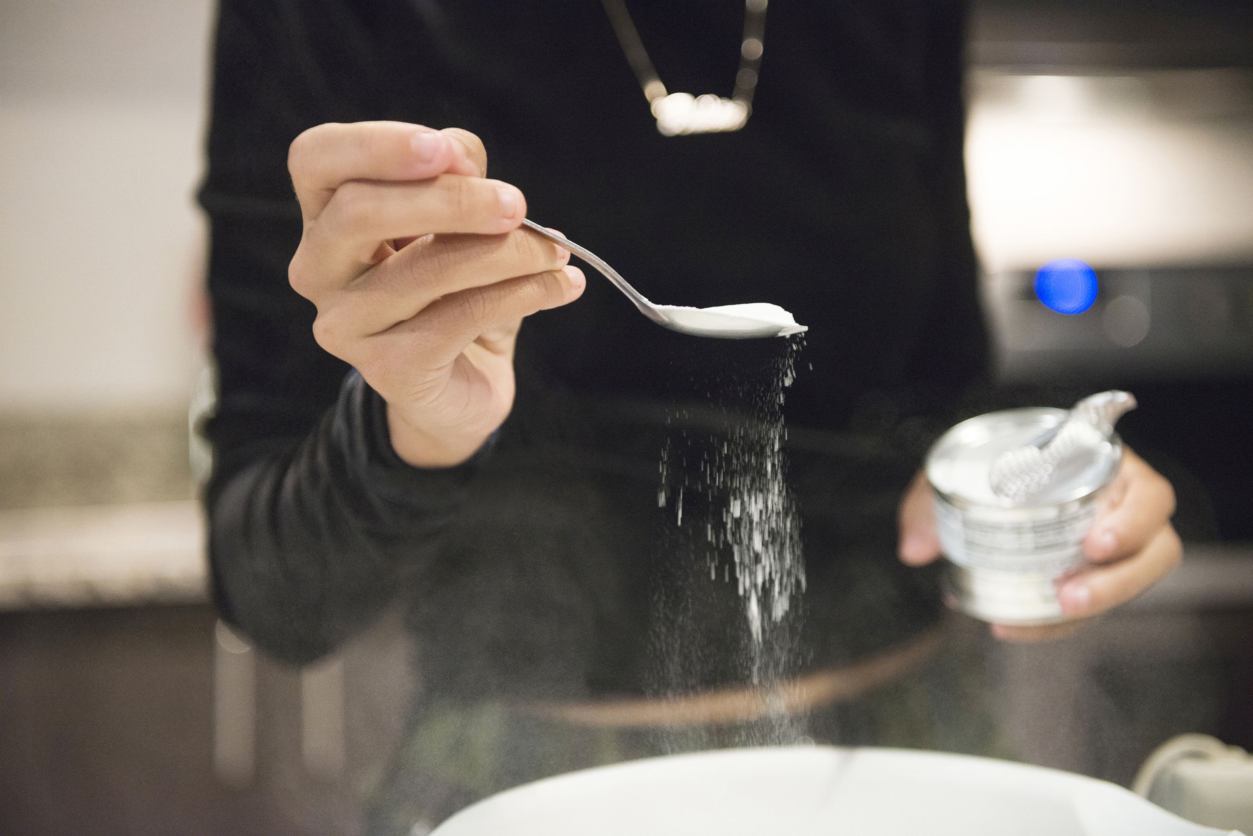 hispanic woman spoons baking soda into batter