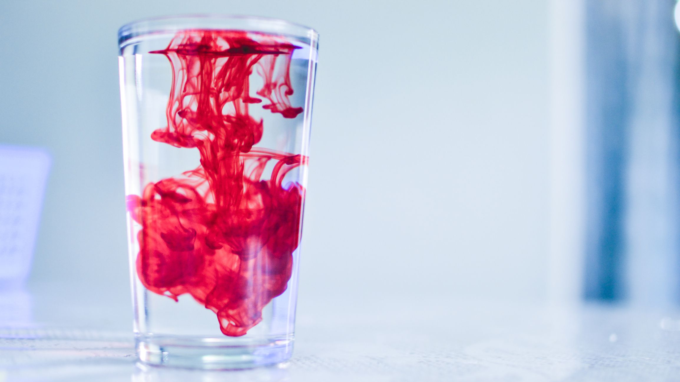 Dispersing red dye in a glass of water with space for text