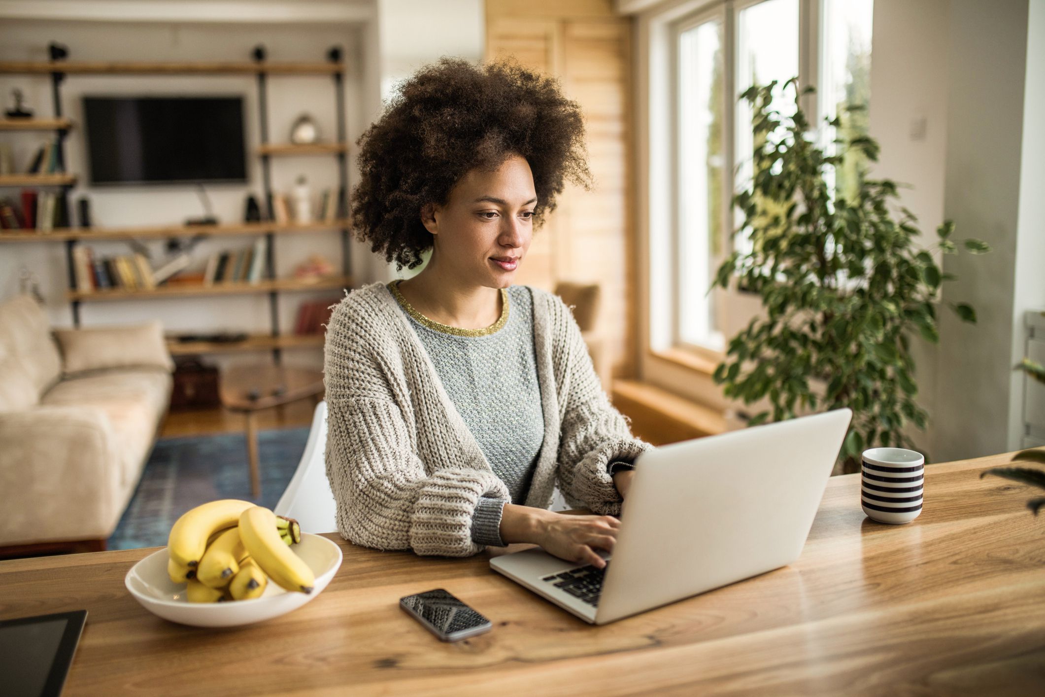 woman typing on her computer while relaxing at home