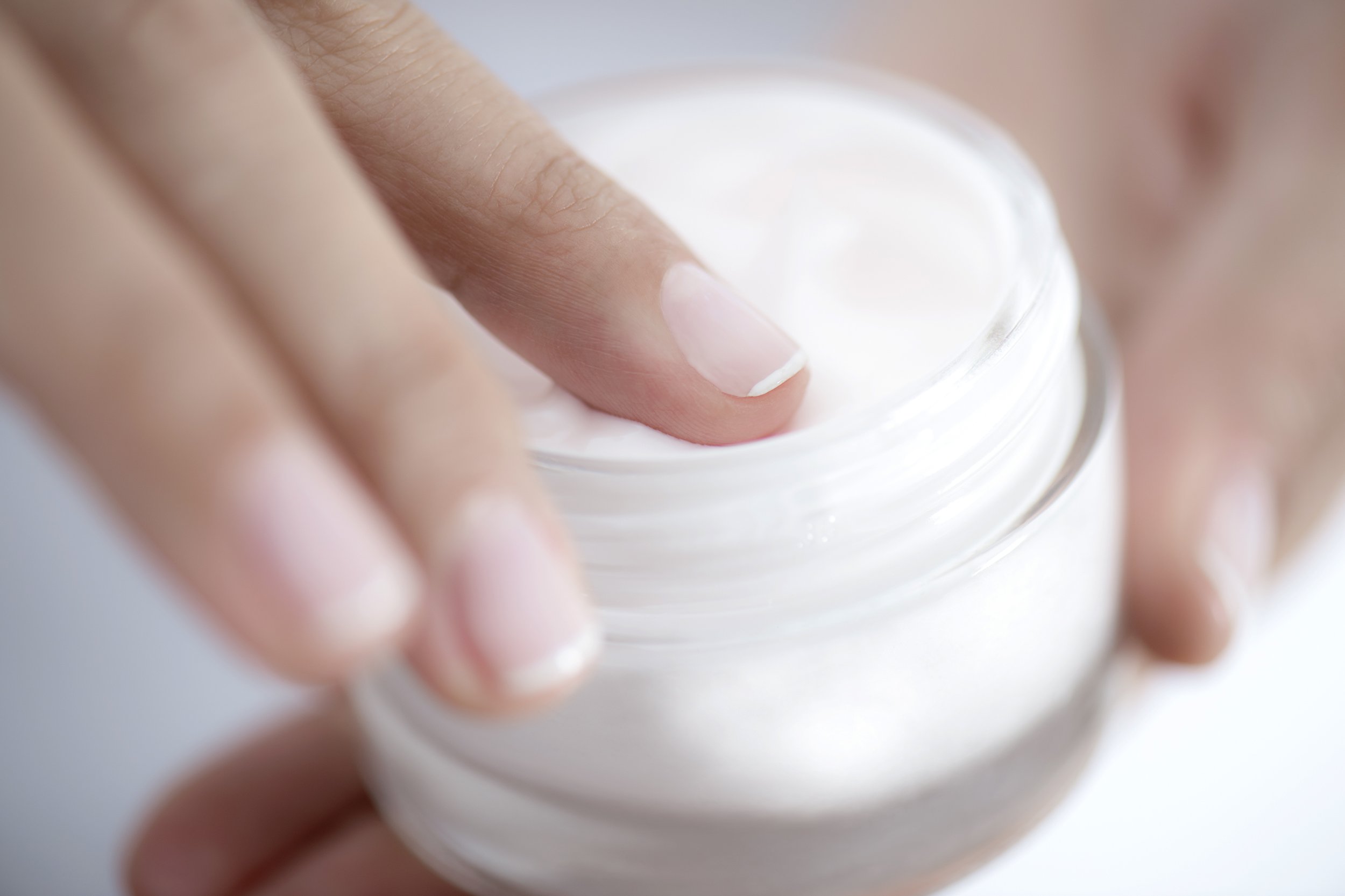 finger on container of moisturizer