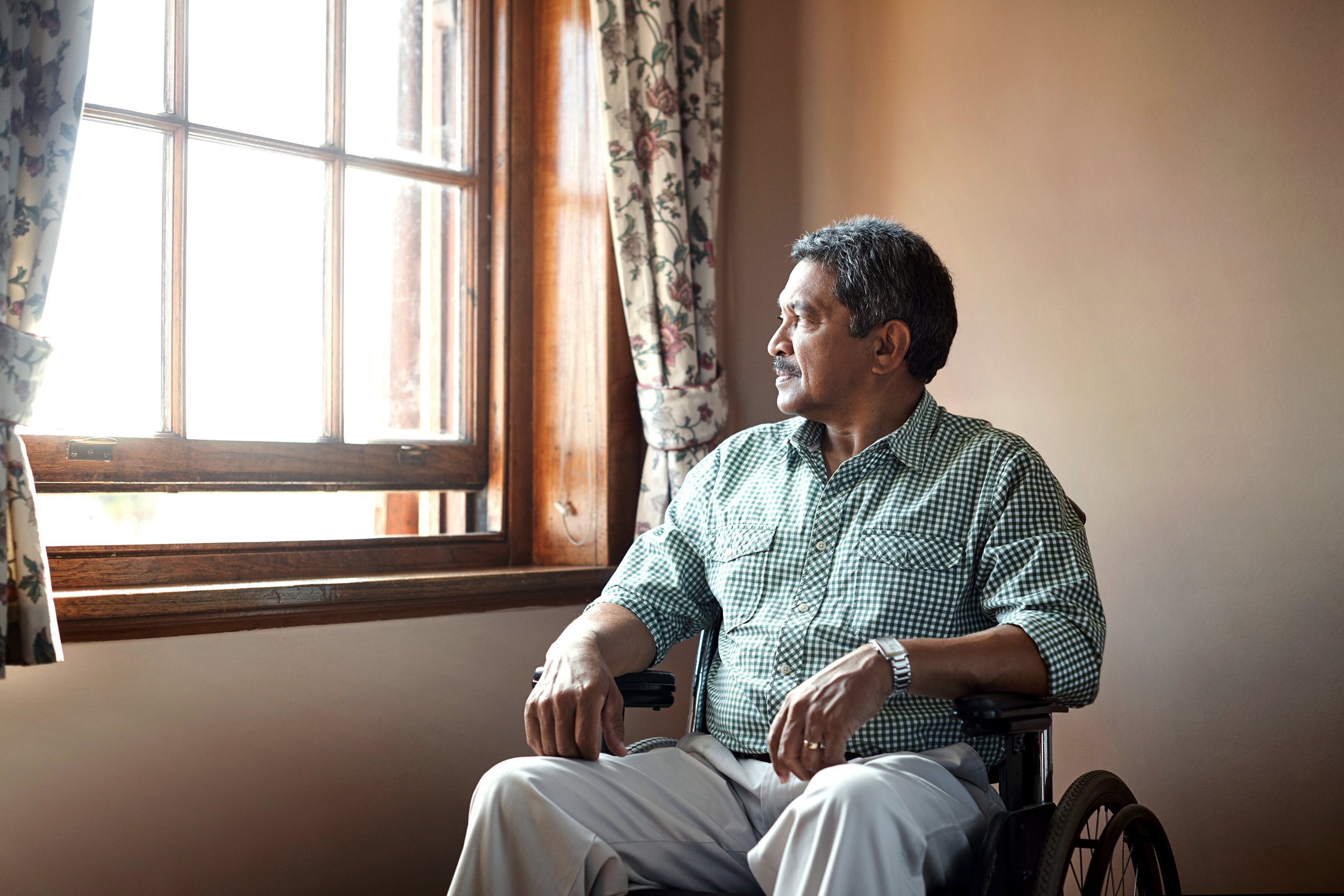 Senior man in a wheelchair looking out the window