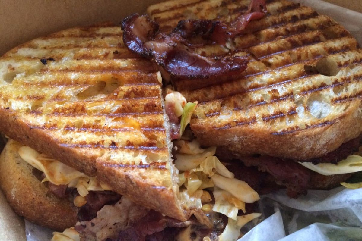 Closeup of Pastrami With Kimchi Slaw Sandwich on white serving paper, Union Market, Richmond, Virginia, in a brown paper container