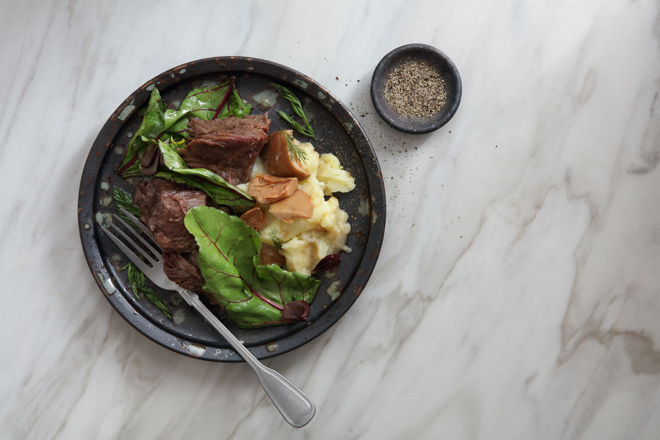 Beef Cheeks in Red Wine with Creamy Mashed Potatoes and saffron milk cap. Flat lay top-down composition on marble background.