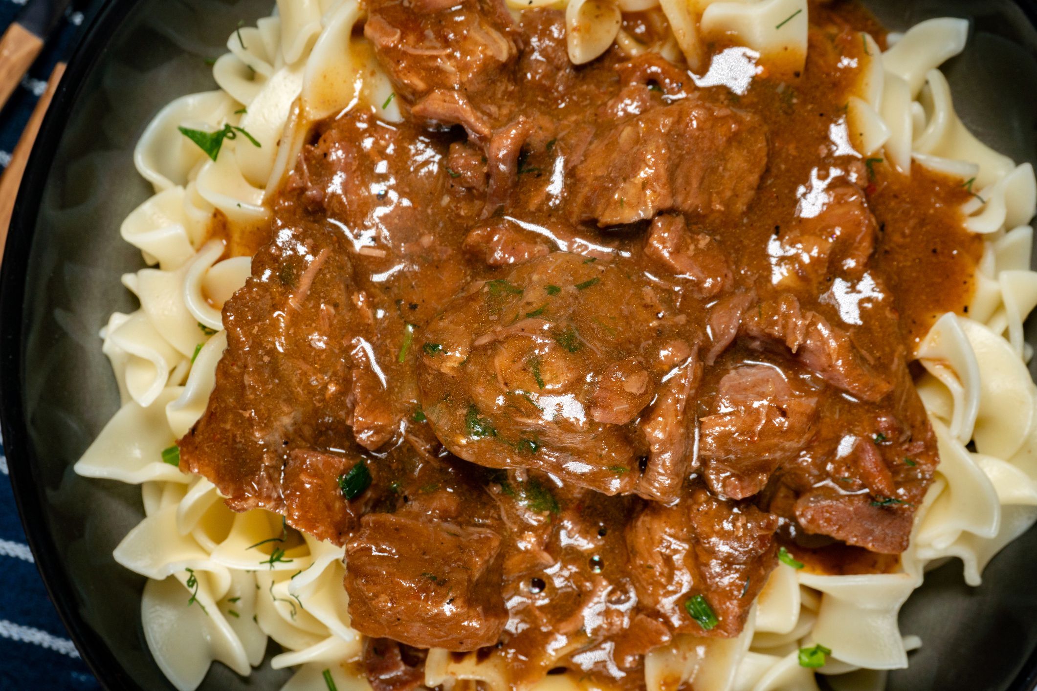 Pasta with beef stew in black bowl. Shallow depth of field.
