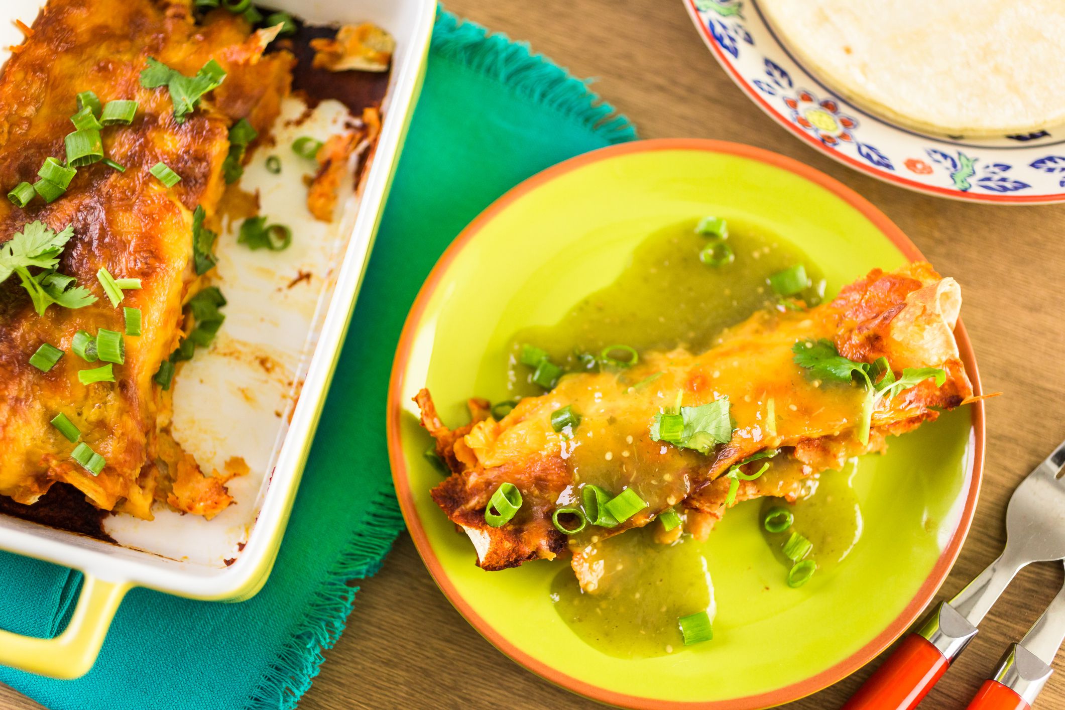 Chicken enchiladas with cheddar cheese and sauce.