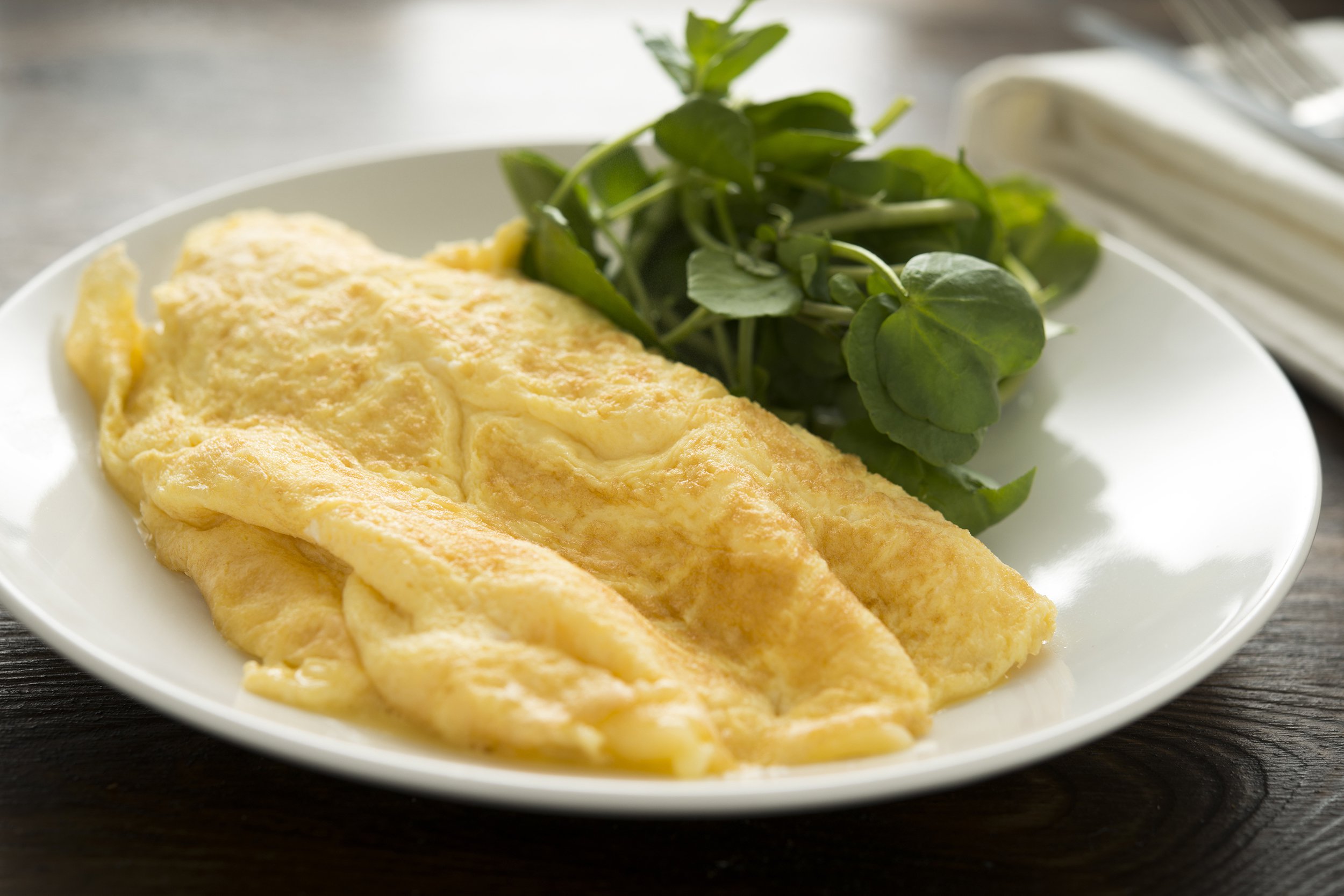 Plain omelet on a plate with greens