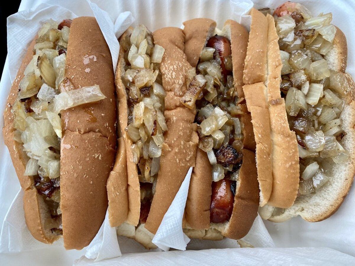 Four Red Snappers with grilled onions surrounded by white napkins on a white Styrofoam container from Wasses Hot Dogs, Rockland, Maine