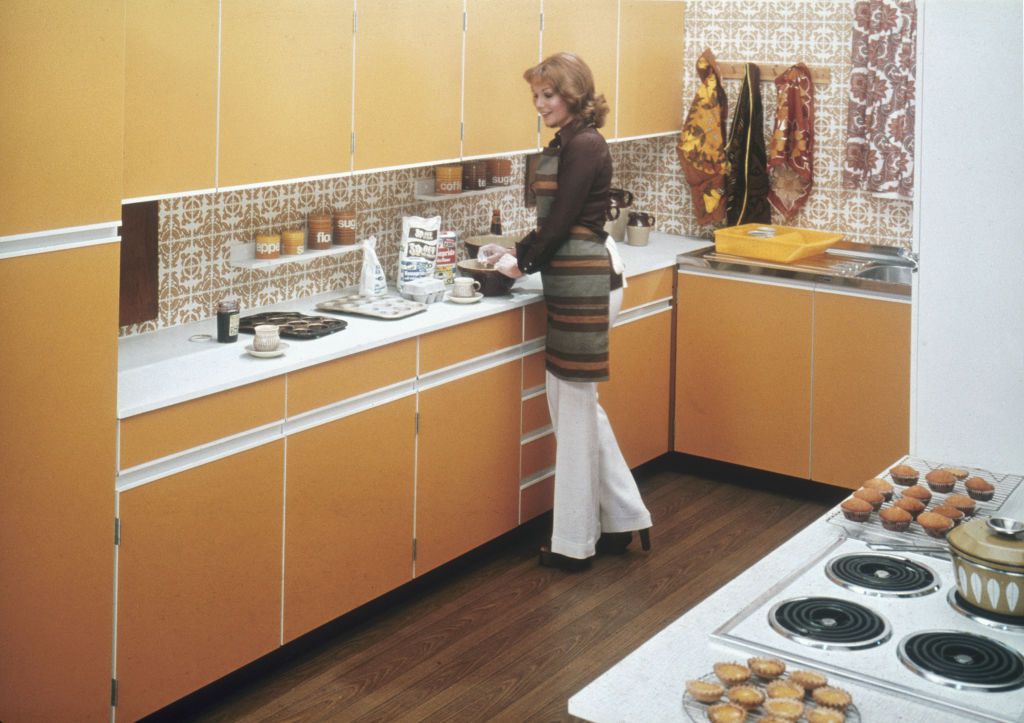 A woman baking cakes in a fitted kitchen, circa 1975.