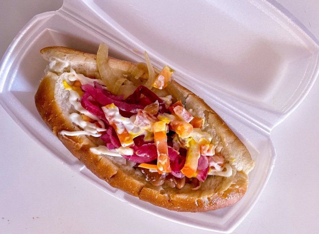 The Sonoran hot dog in a white container on a white table at El Guero Canelo Restaurant, Tucson, slight diagonal