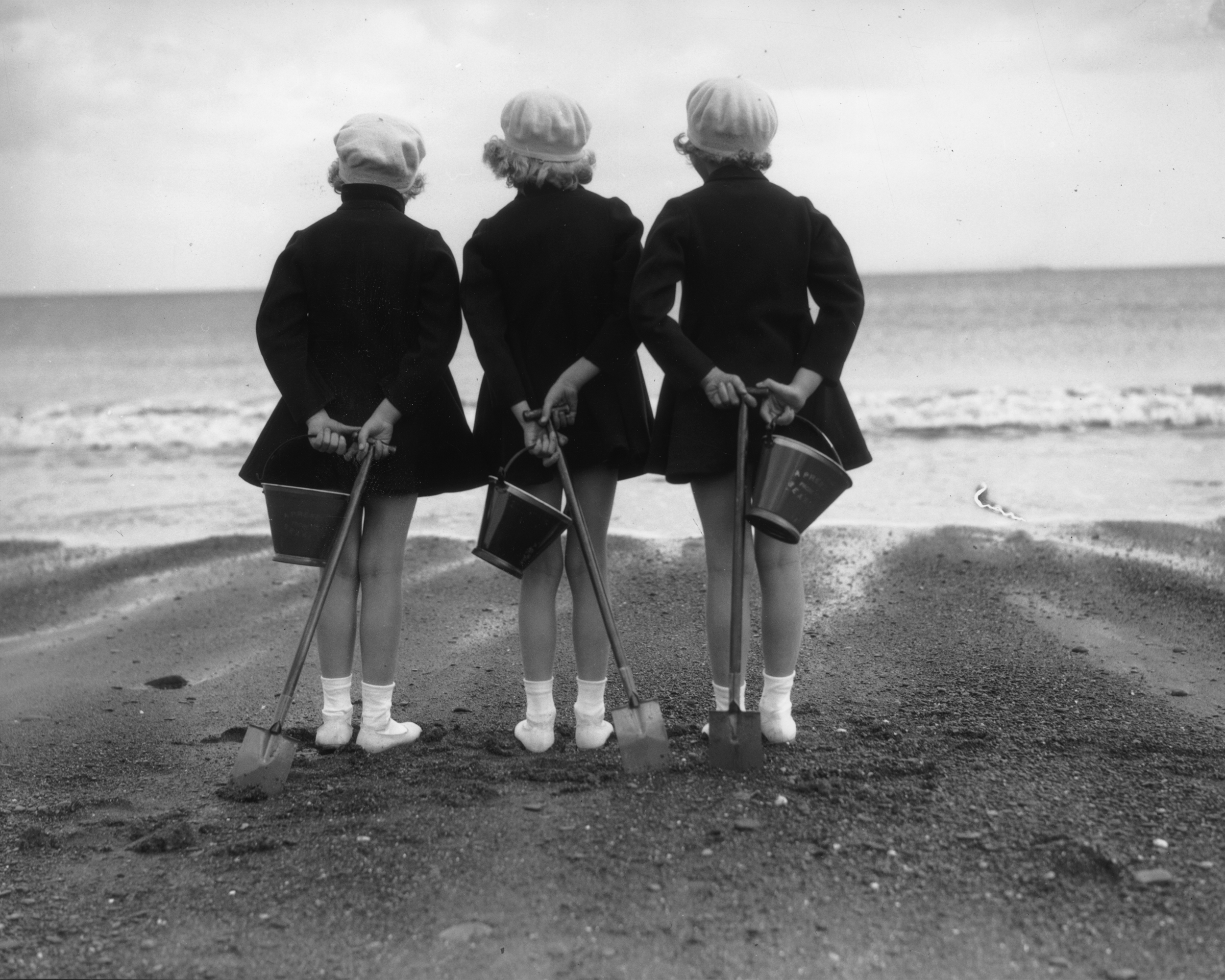 Wearing coats and berets against the chill of an English summer three children have brought their buckets and spades to the beach at Whitby in Yorkshire