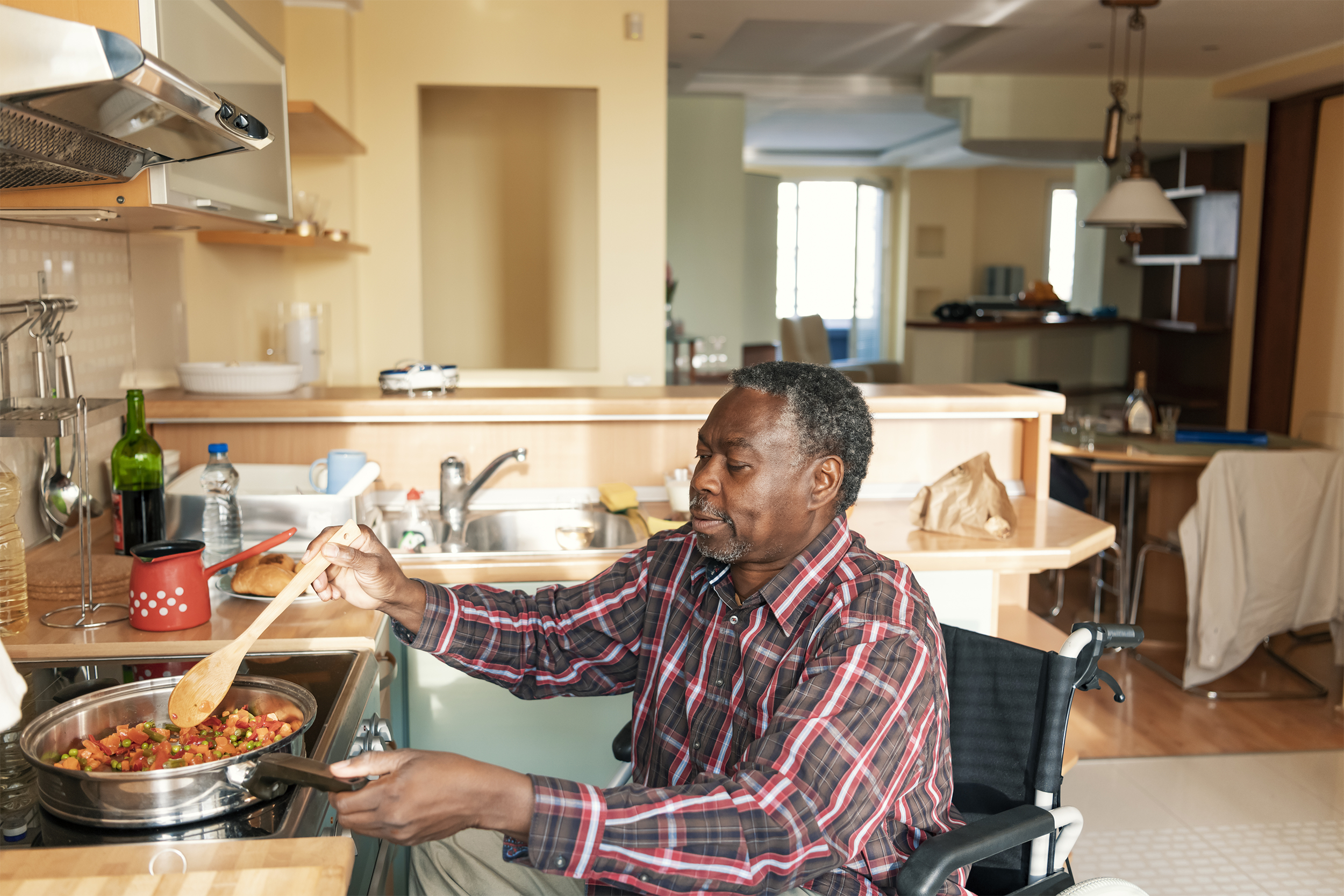 Black man in a wheelchair cooking dinner at home