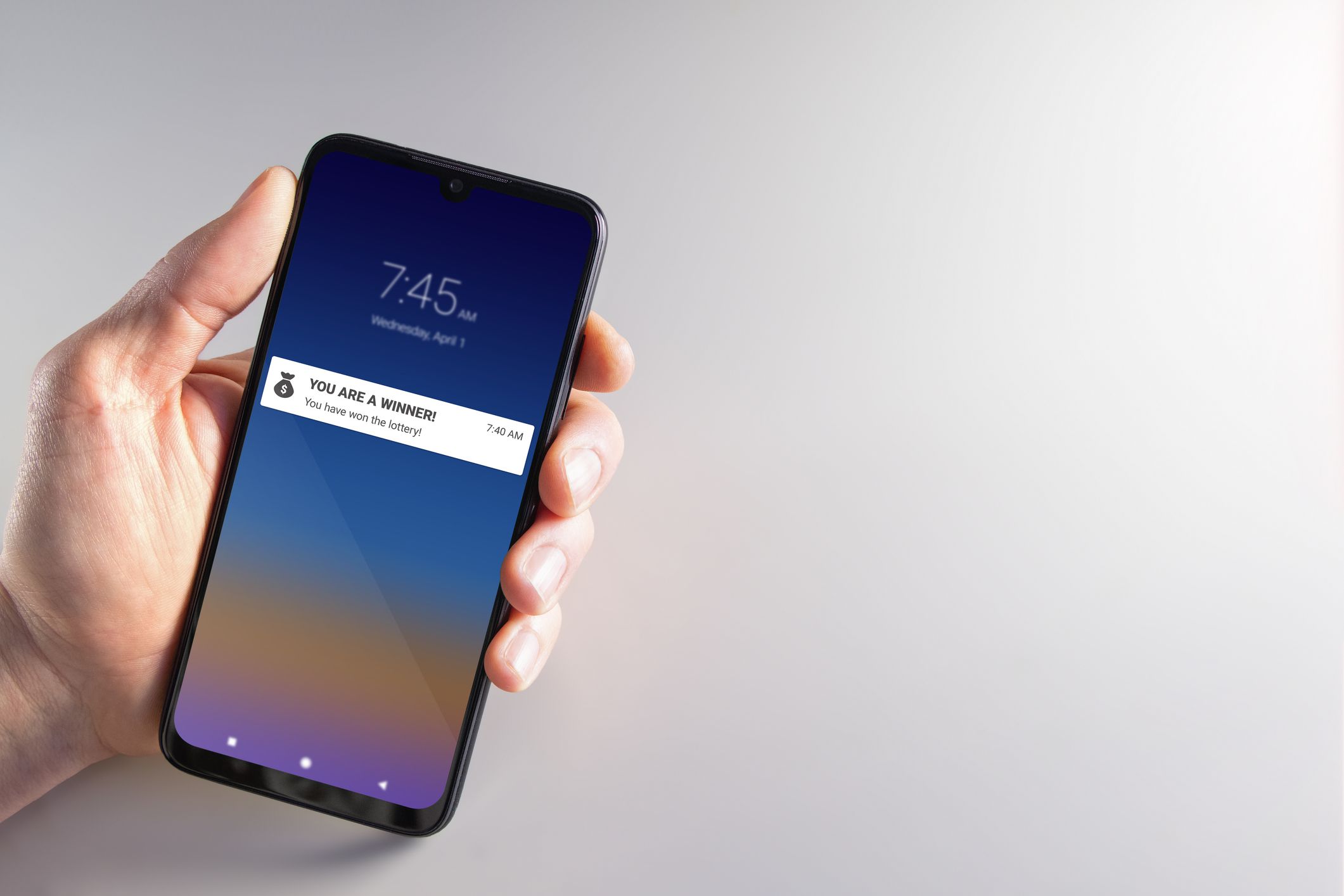 Male hand holding a smartphone with lottery winner notification on April 1st. Scam, April fools, cybercrime, privacy and technology concepts.