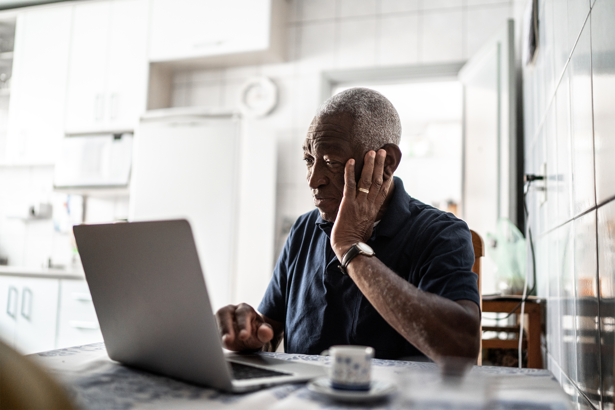 senior man worried working on laptop at home