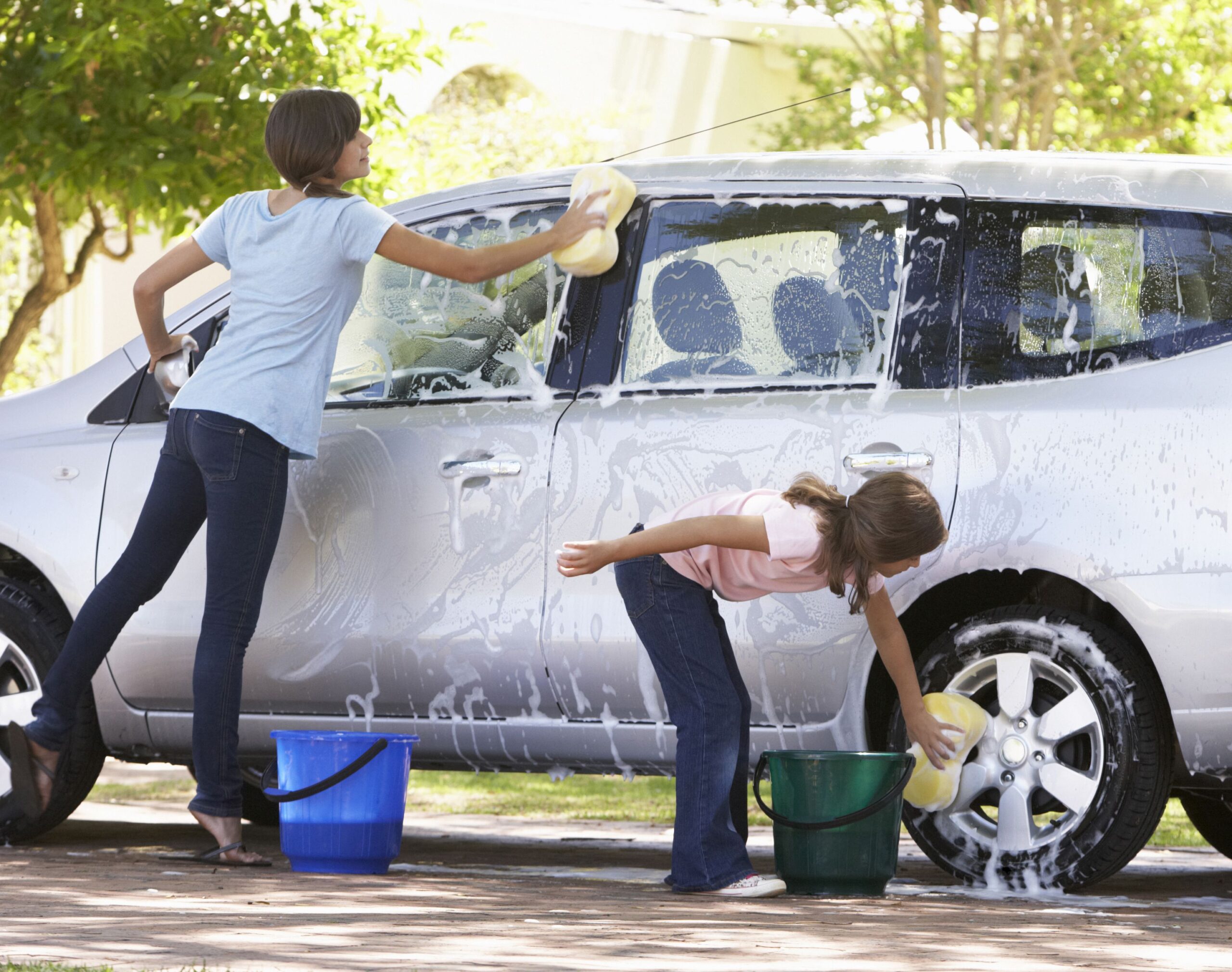 Two Girls Outside Washing Car Together.