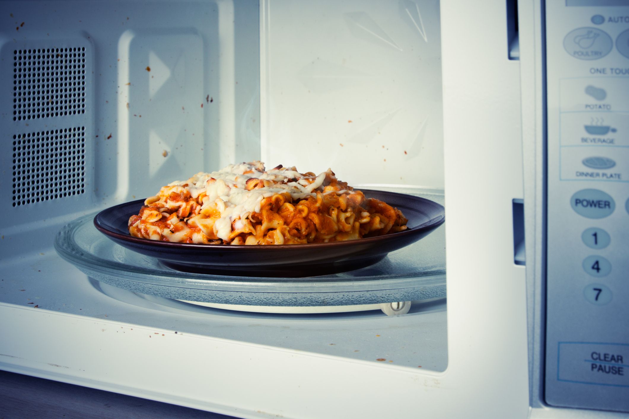A plate of leftover lasagna is reheated in a microwave.