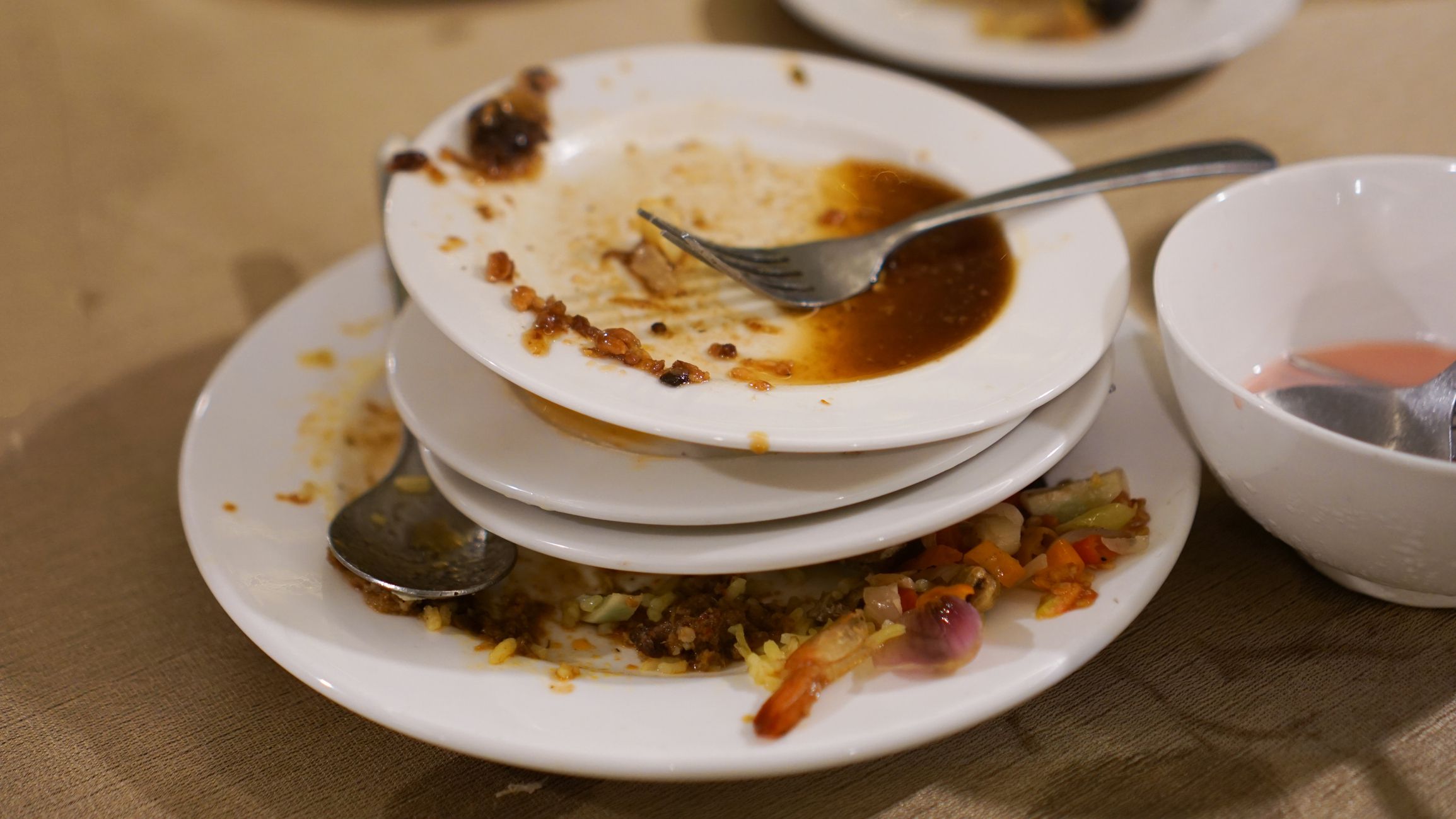 ultiple soiled dishes stacked after dining, showcasing traces of meals and a used fork
