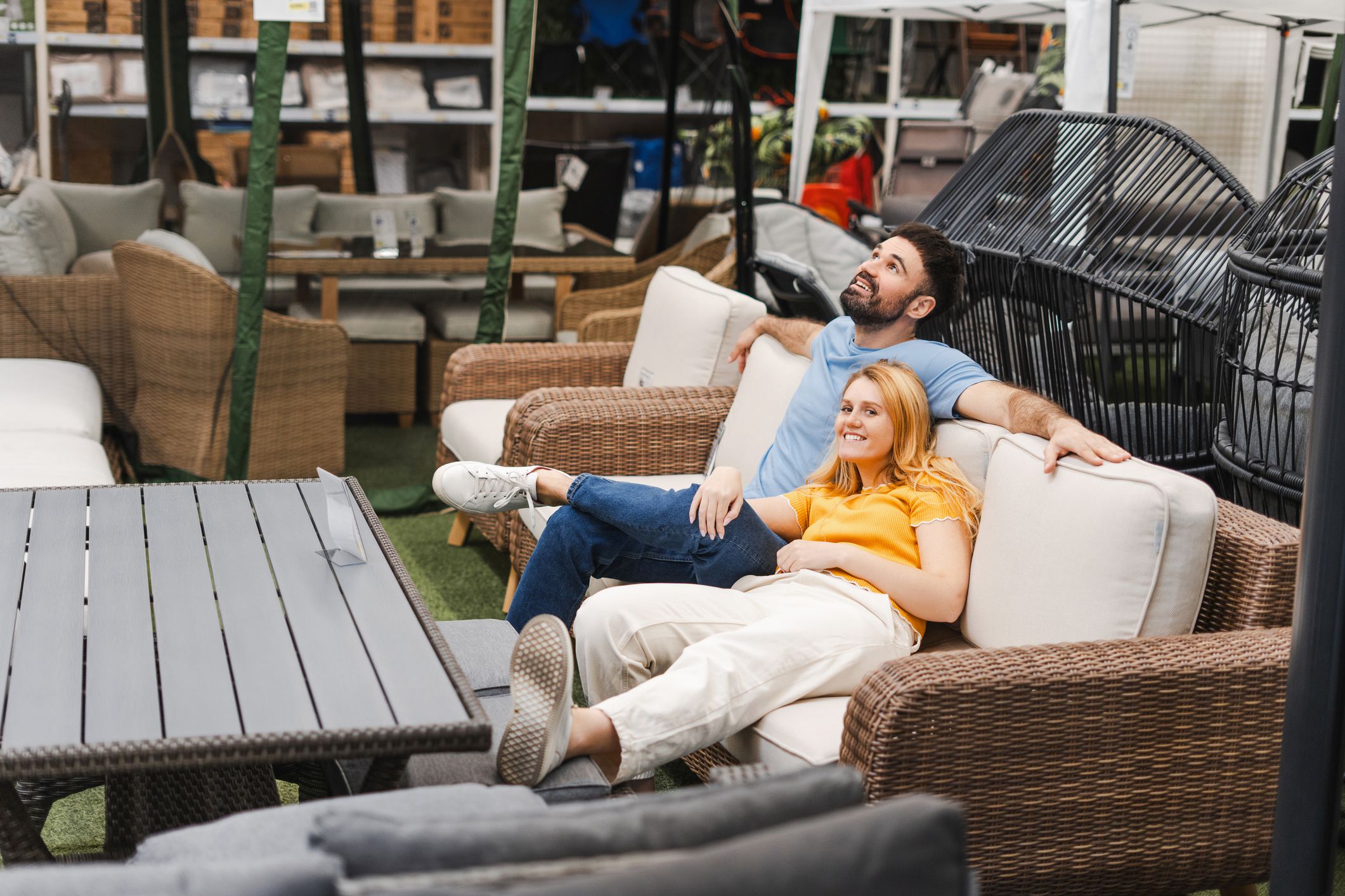 Portrait of smiling loving young couple sitting on the sofa garden terrace in the furniture department of store
