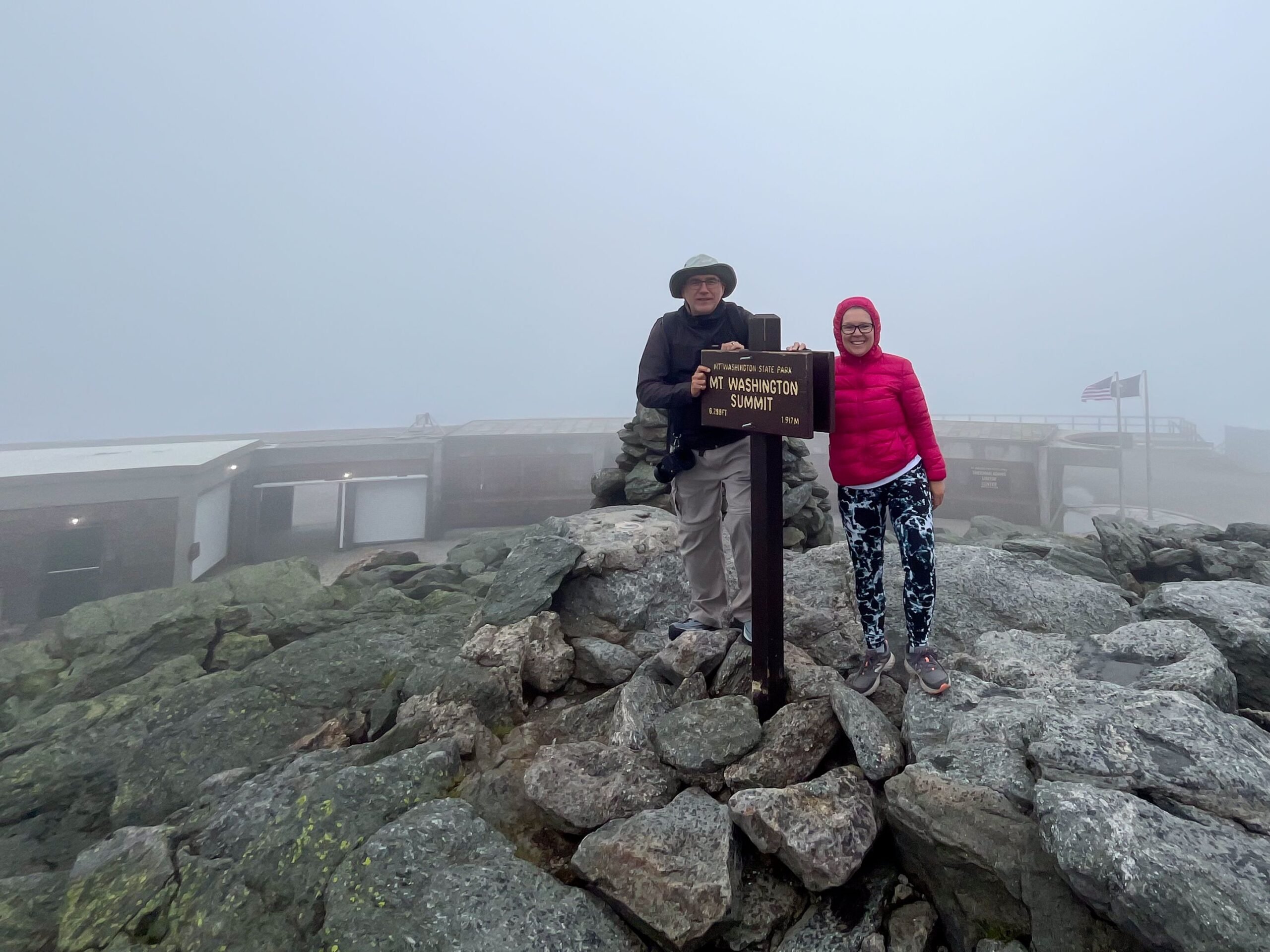 Mature woman and man at the top of Mount Washington during a foggy summer day
