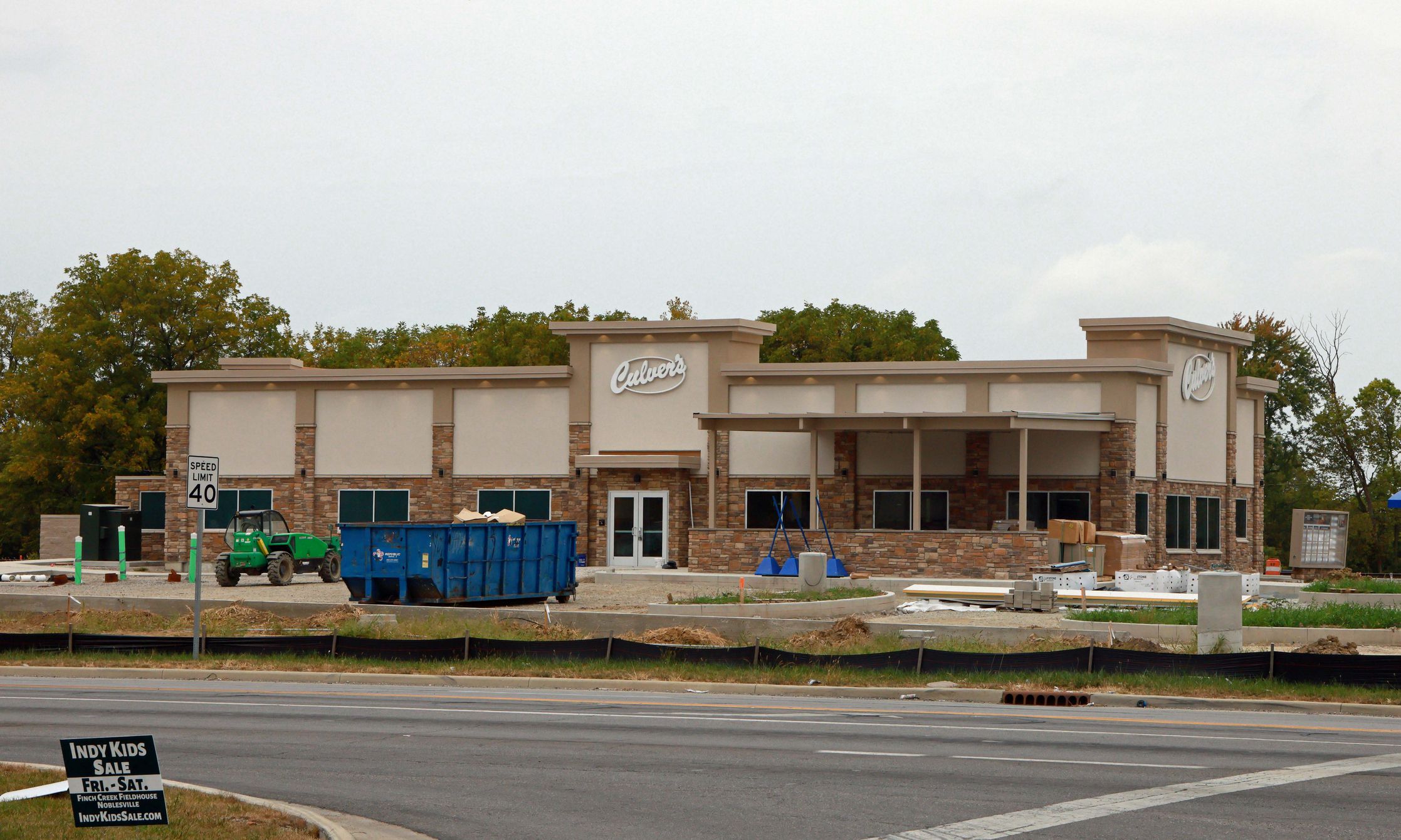 McCordsville, Indiana, USA -September 22 2024: A commercial real estate restaurant building under construction, featuring partially installed stone veneer and windows, with an unfinished parking lot and sidewalks.