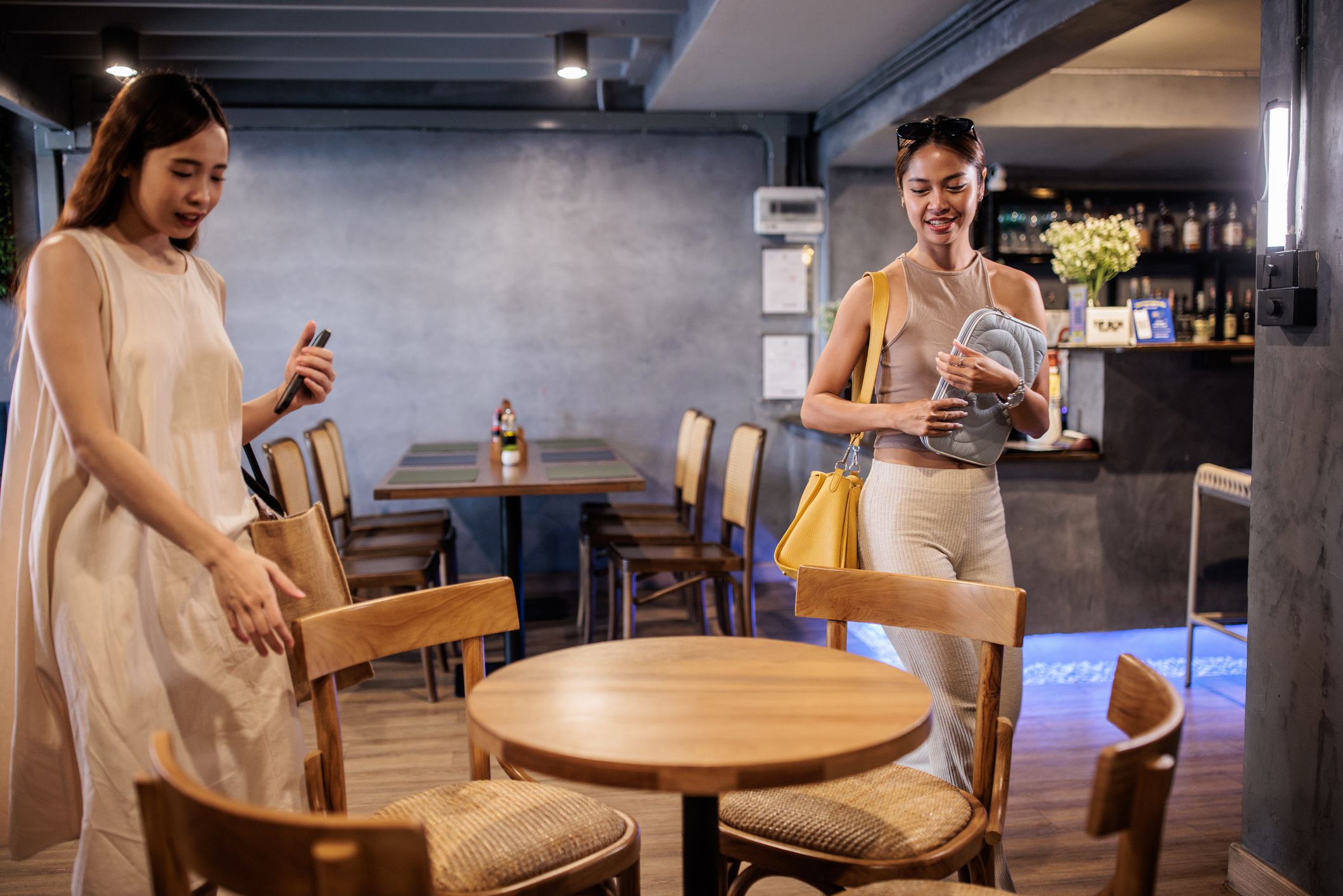 Two Thai women arriving at a trendy cafe and looking where to sit.