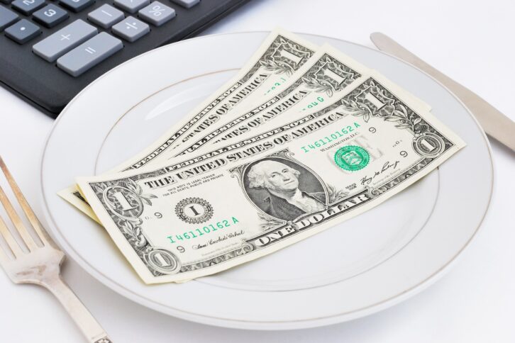 three dollars on plate with calculator in the background