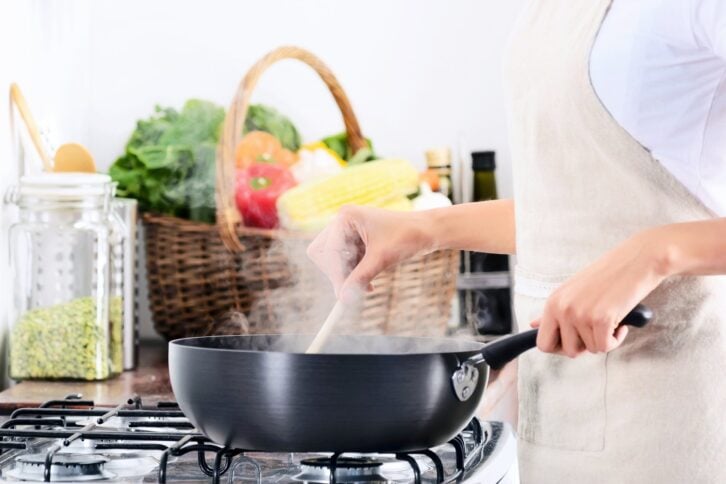woman cooking by the gas stove with a steaming pot