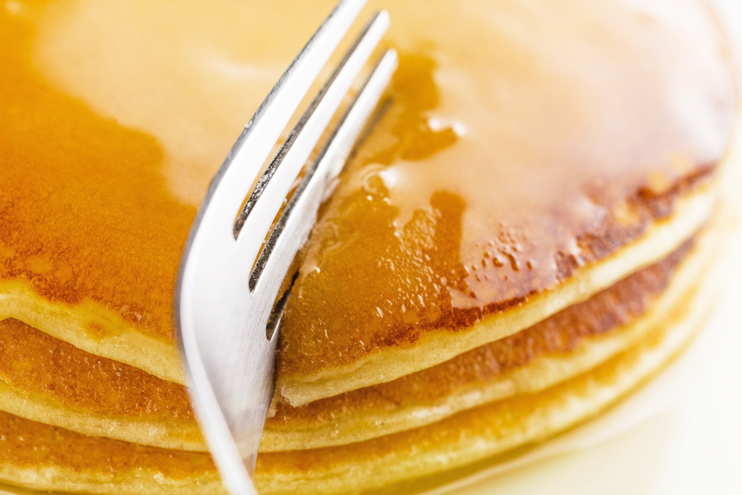 fork cutting pancakes on plate