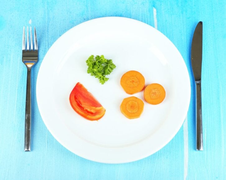 small portion of food on big plate on wooden table