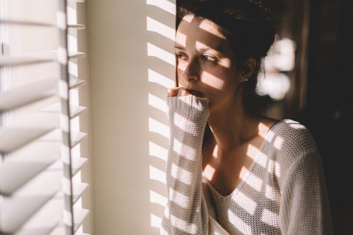 sad woman looking through the window