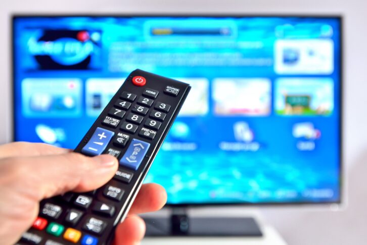 smart tv and hand pressing remote control