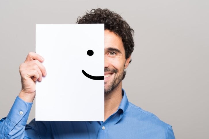 happy man covering half his face with a smiling emoticon