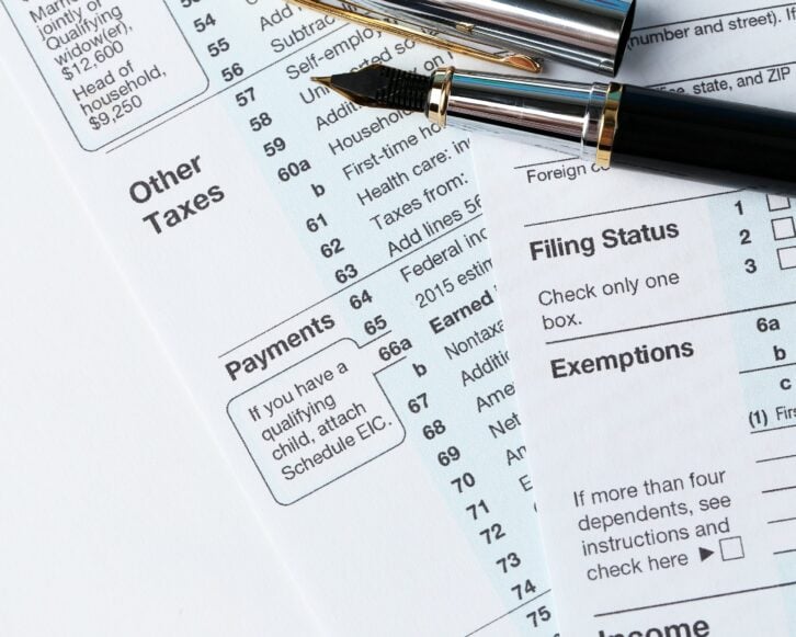 1040 Individual Income Tax Return Form for 2015 year with a pen to fill on the white desk