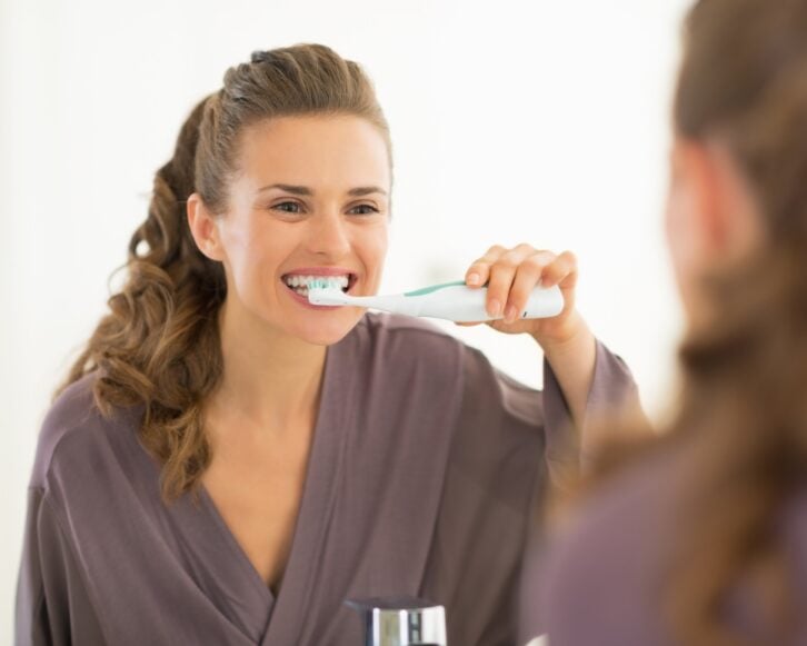 woman brushing teeth in bathroom