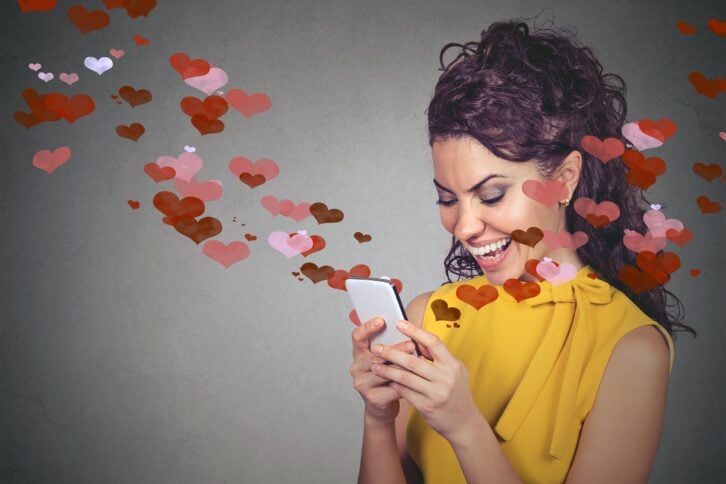 happy woman sending love text message on mobile phone with red hearts