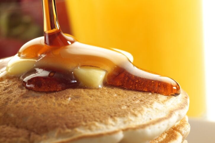 maple syrup being poured on pancakes
