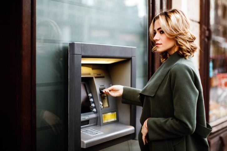 Woman looking cautious while using an atm in the city