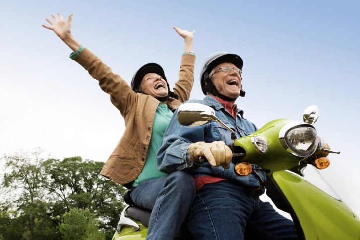Senior couple riding on a scooter outside having fun