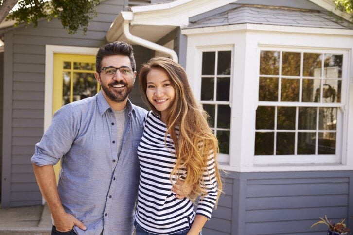 Happy young couple in front of their new house