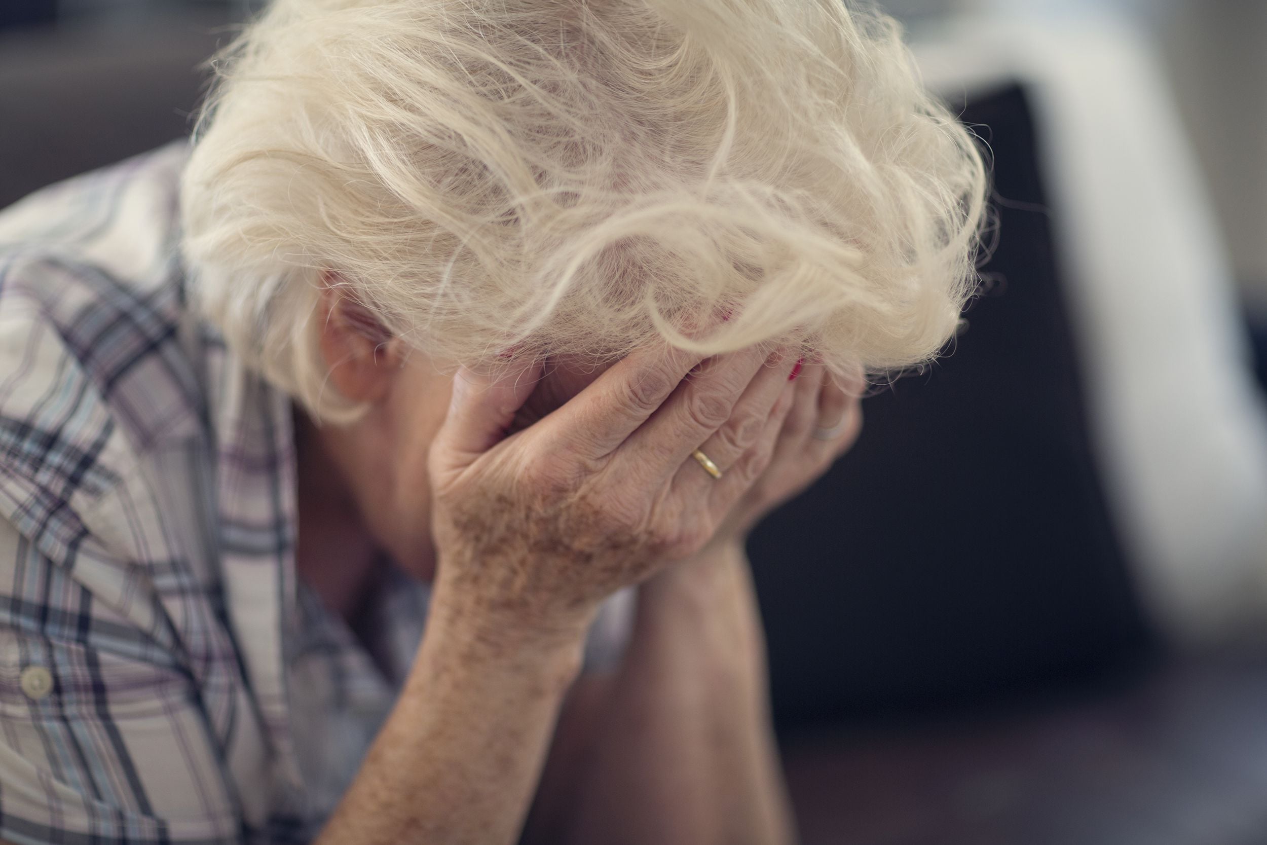 senior woman holding head in hands in despair